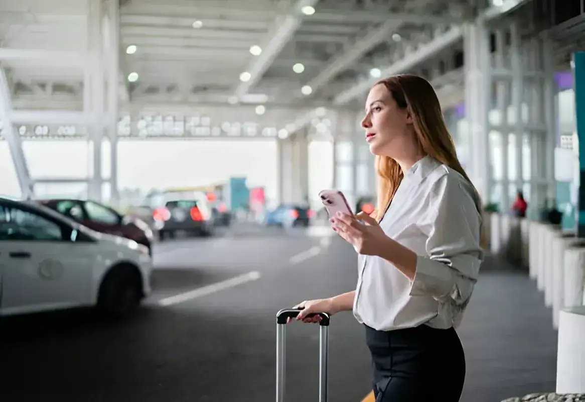 Passenger waiting with luggage at an airport taxi area