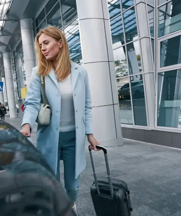 Traveller with suitcase meeting a taxi at an airport terminal